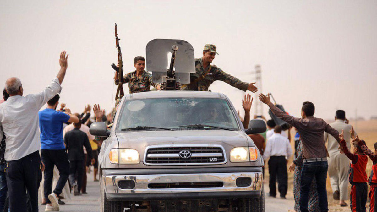 Civiles sirios saludan a tropas de Al Asad en la ciudad de Tel Tamer, en el noreste del país.