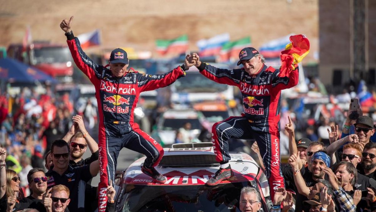 Carlos Sainz i el seu copilot, Lucas Cruz, celebren el triomf al Dakar a damunt del seu vehicle.