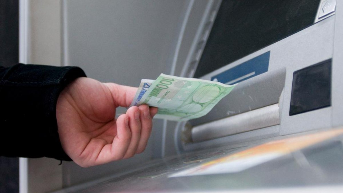 Imatge d’un client traient diners d’un caixer automàtic.