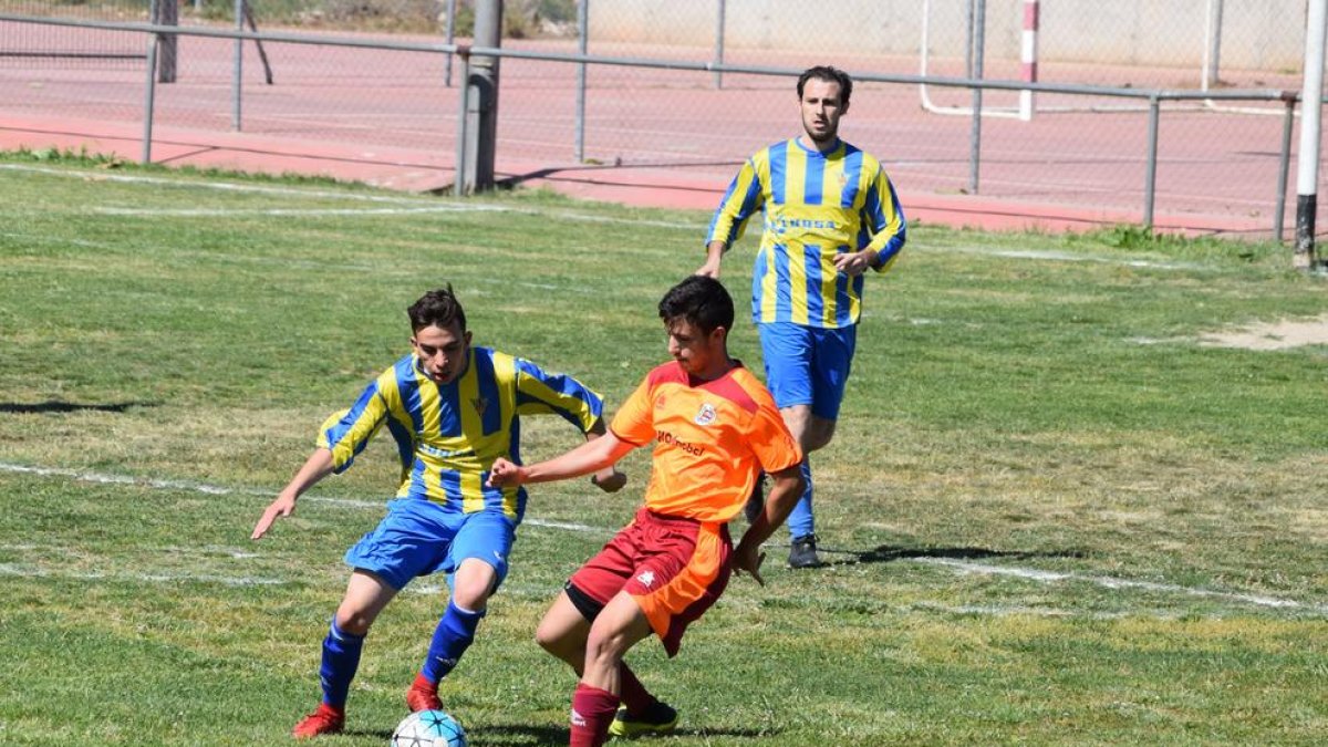 Un jugador del Rosselló disputa la pilota davant la presència de dos rivals.