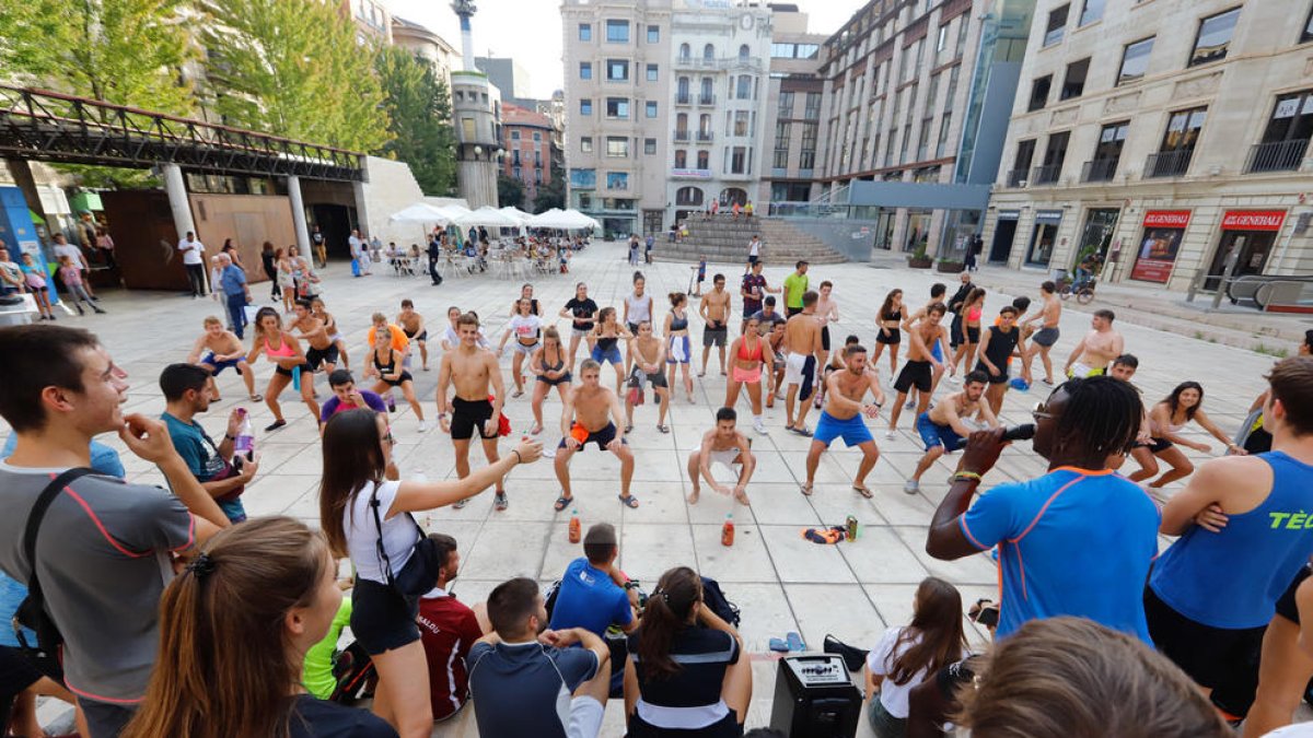 Alumnes bevent i fent flexions com a part de les novatades, ahir a la plaça Sant Joan.