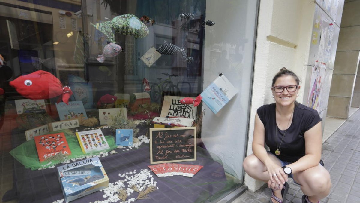 La librera de El Genet Blau, Marina Guillén, junto al escaparate distinguido por la Setmana del Llibre.