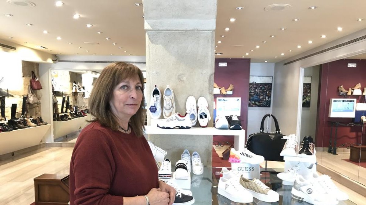 Una empleada de una óptica de Lleida enseña varias gafas a una clienta.