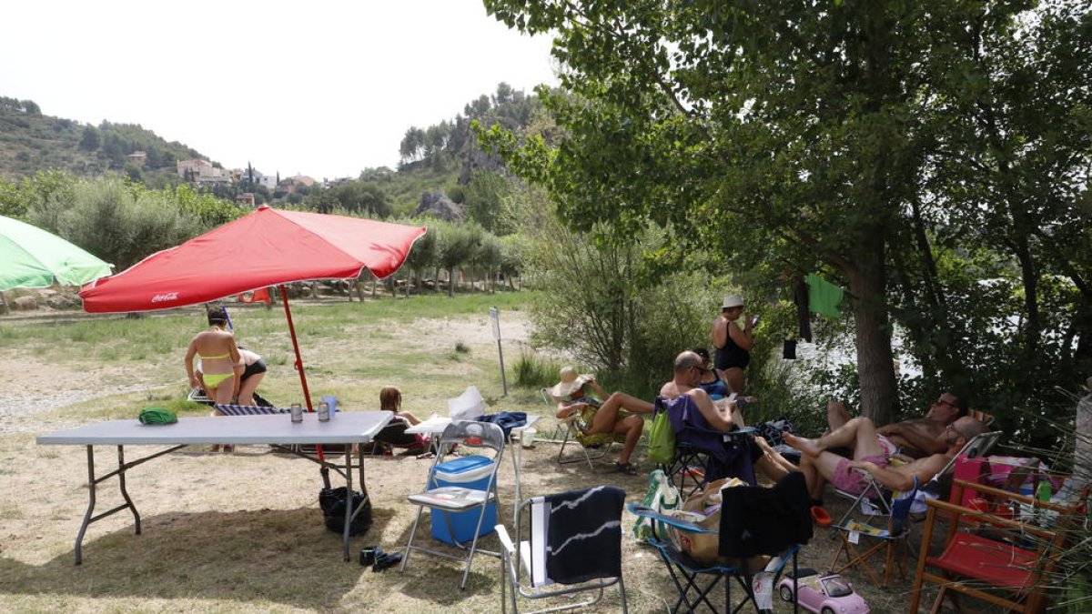 Mesas de picnic, tumbonas y sombrillas en la ribera del río Segre en Camarasa.