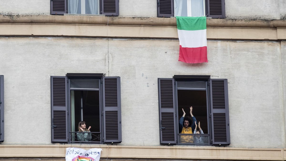 Italianos aplaudiendo ayer a los sanitarios desde sus casas.