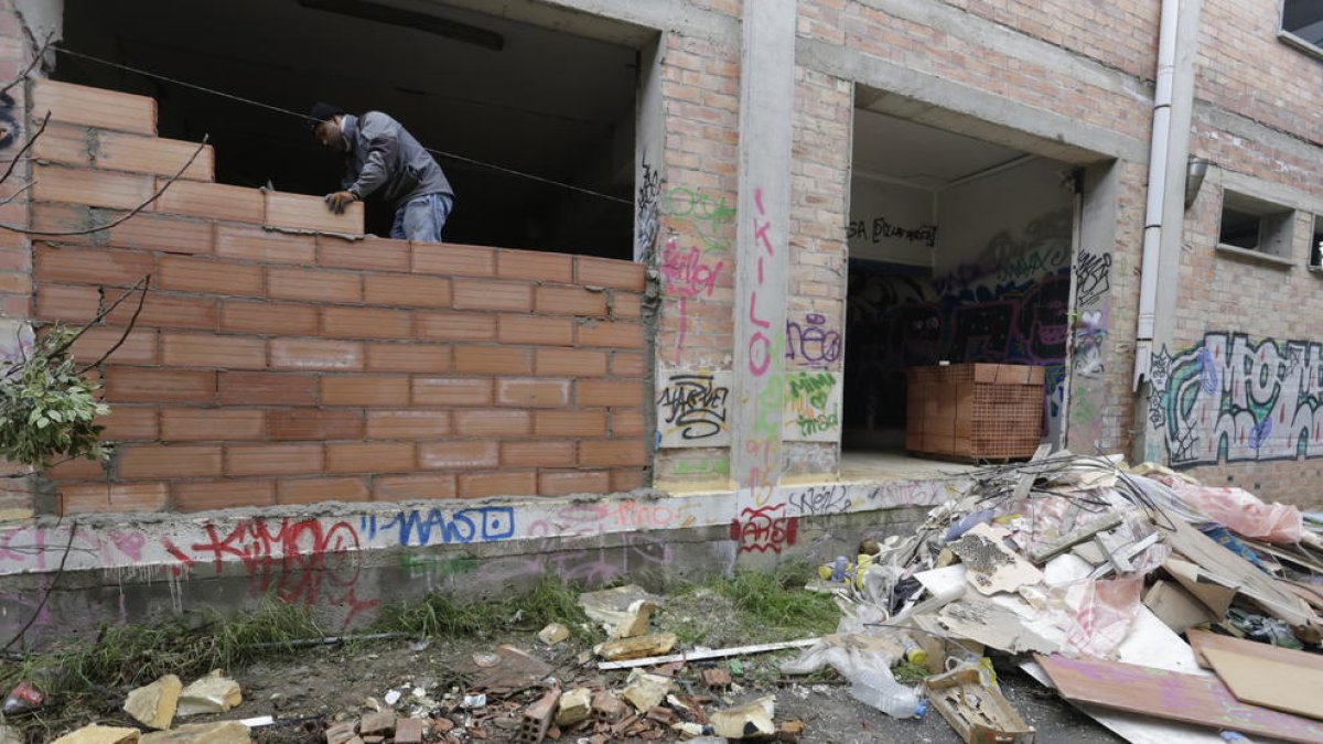 Un operari treballa en les tasques per tapiar la nau abandonada a Rufea.