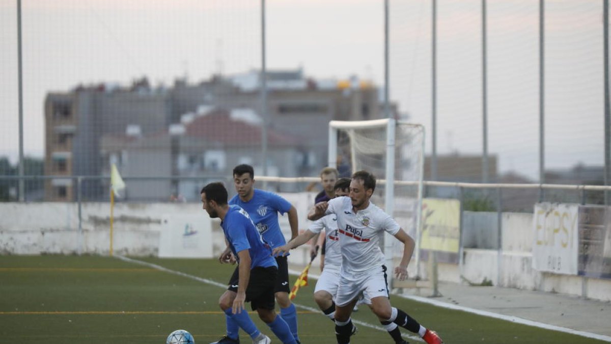 Un jugador de l’Alcarràs protegeix la pilota, perseguida per dos futbolistes del Borges.