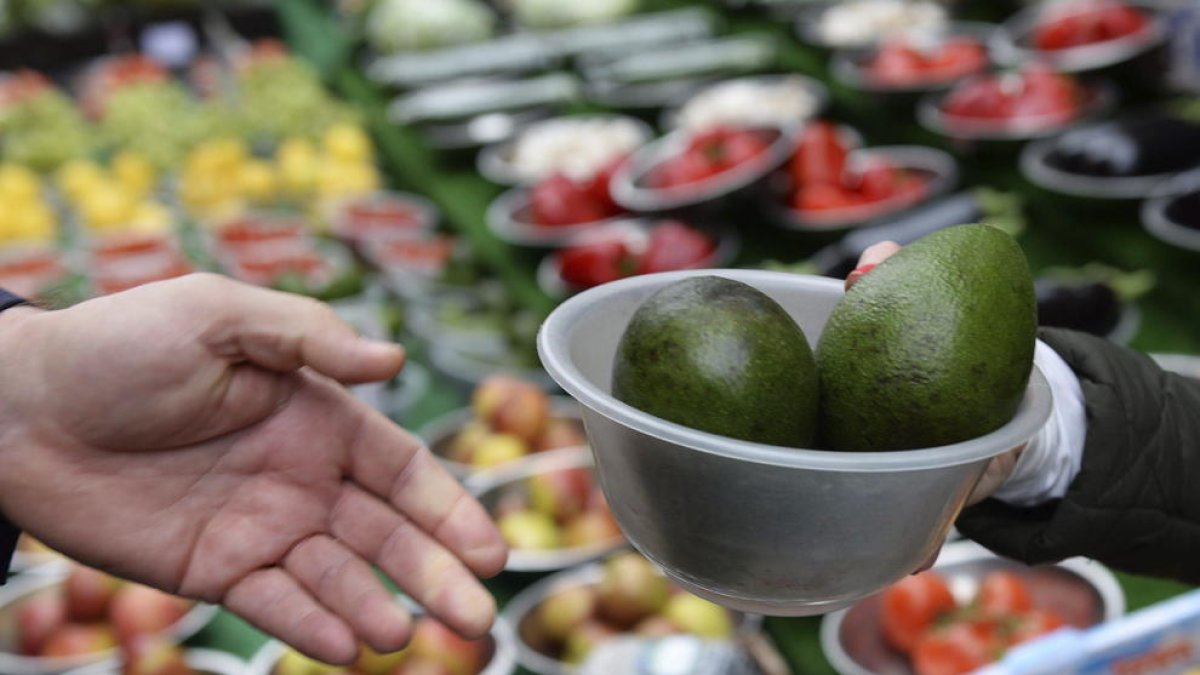 Un cliente compra aguacates en un mercado.