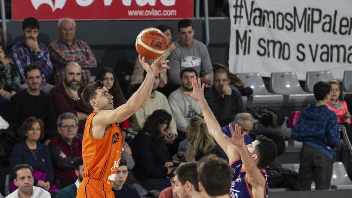 Adriàn Chapela lanza a canasta ante la oposición de un rival.