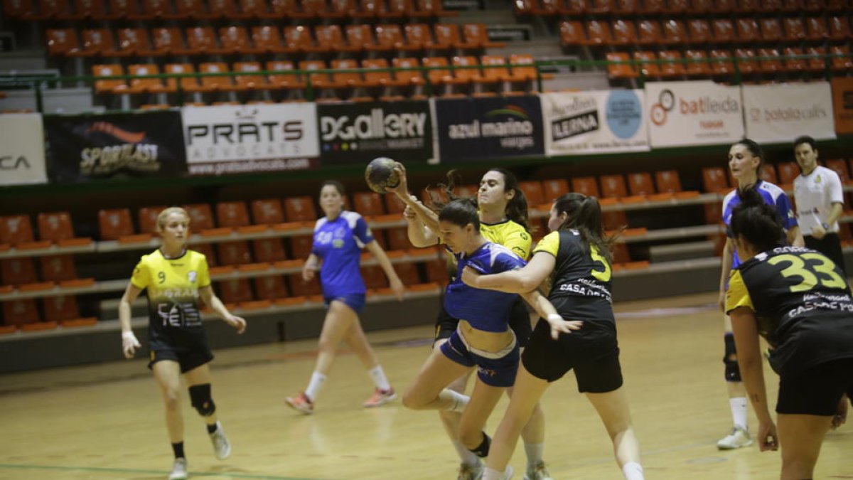 Una jugadora de la Associació Lleidatana d’Handbol intenta tirar, sujetada por otra del Amposta.