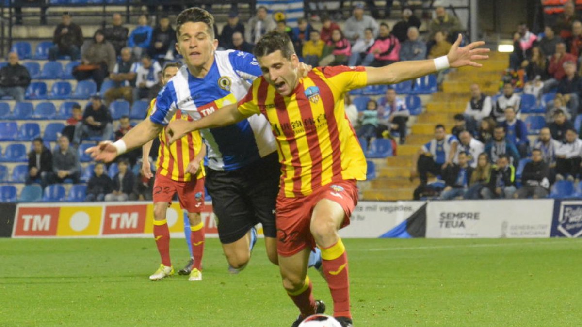 Juanto Ortuño avança amb la pilota agafat per un jugador de l’Hèrcules.