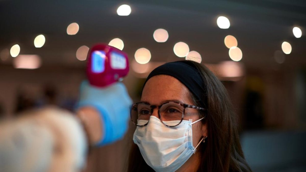 Un empleado mide la temperatura de una socia antes de entrar al gimnasio.