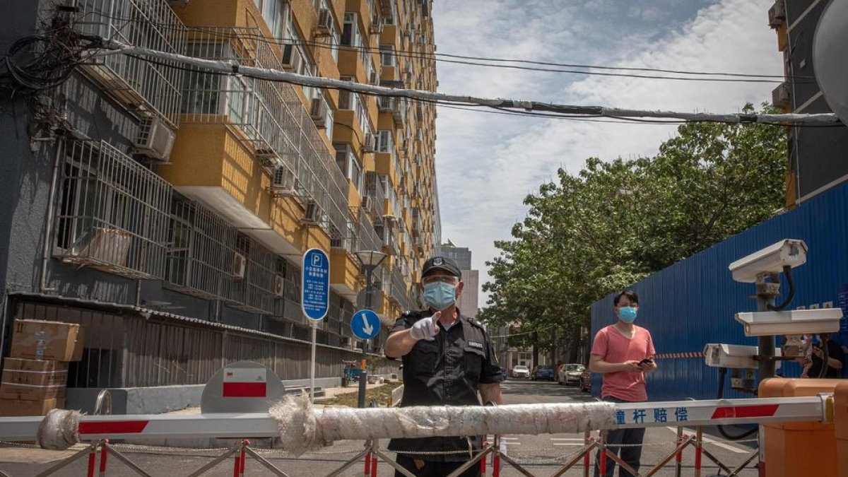 Un guardia de seguridad impide el paso a una calle cercana al mercado de Pekín infectado por Covid-19.