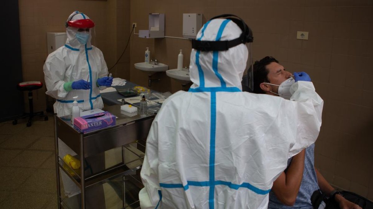 Dos técnicos realizan una prueba PCR a un paciente.