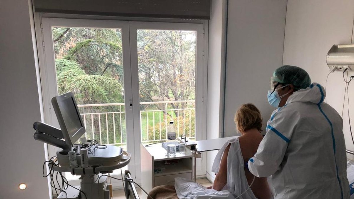 Una dona ingressada per Covid a l’Arnau de Vilanova és atesa per un sanitari de l’hospital.