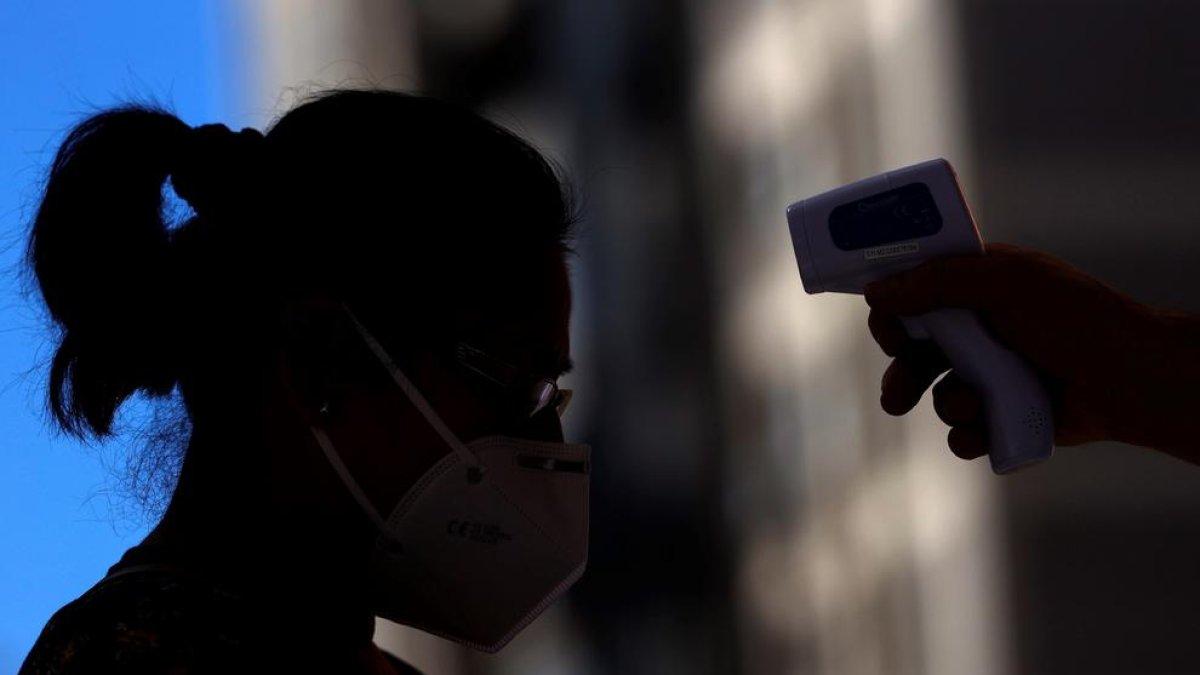 Un sanitario toma la temperatura a una mujer