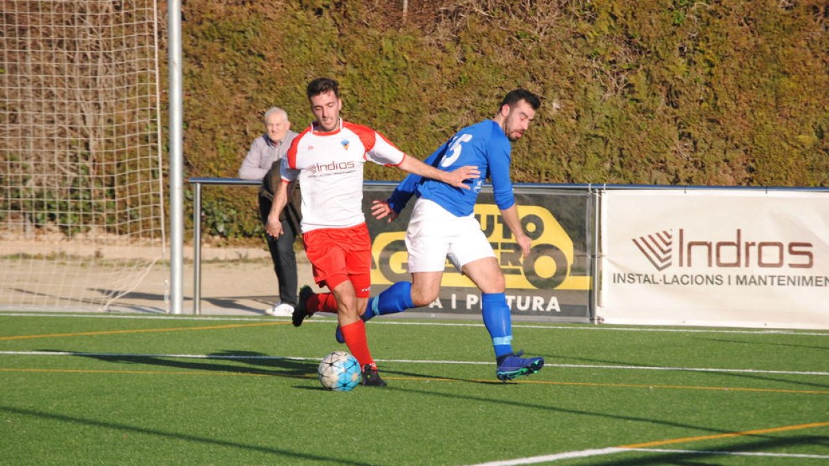 Un jugador local intenta controlar la pilota davant de la pressió d’un visitant.