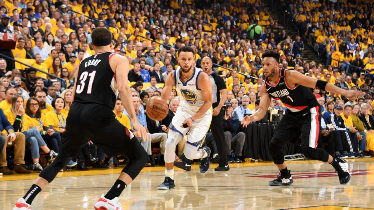 Stephen Curry porta la pilota davant del seu germà Seth.