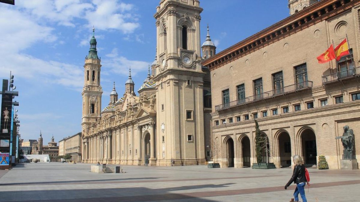 Una mujer pasea a un perro en Zaragoza por una plaza del Pilar completamente vacía.