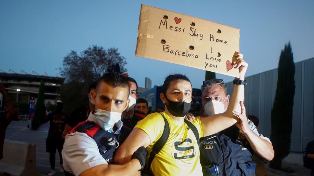 Dos agentes de los Mossos detienen ayer a uno de los manifestantes contra la junta del Barça.