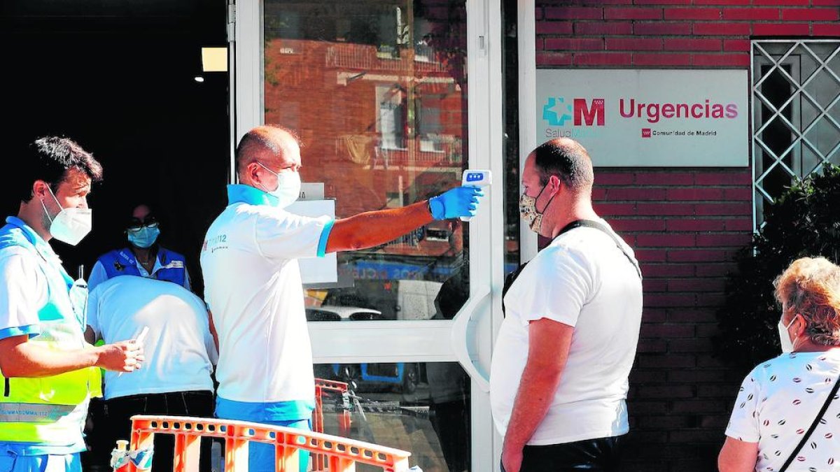 Un paramédico toma la temperatura a la salida de un centro sanitario de San Sebastián de los Reyes.