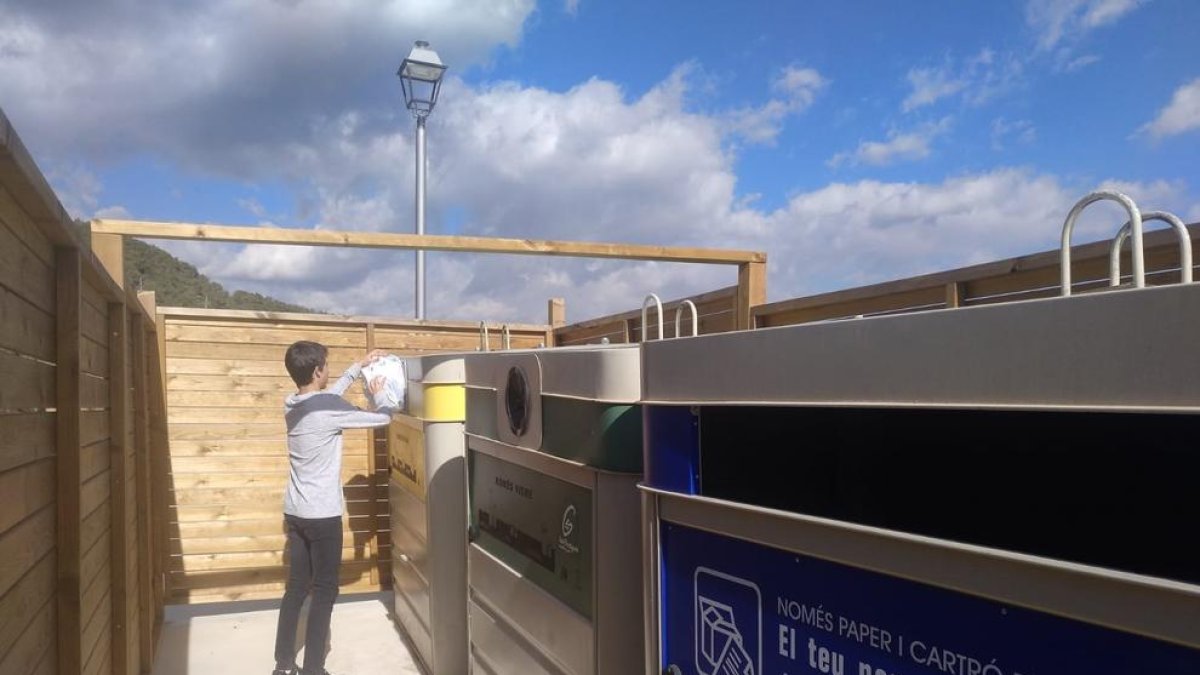 Un nen diposita escombraries als contenidors de Tarrés.