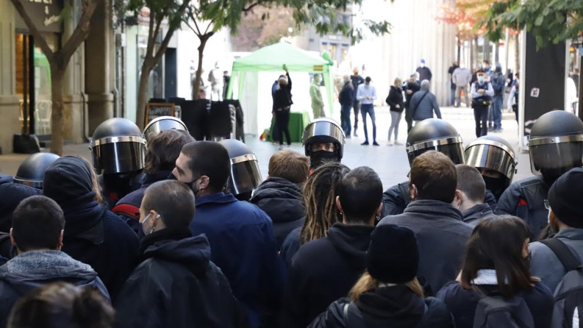 En primer plano, los manifestantes y los antidisturbios. Al fondo, el estand de Vox en la calle Major.