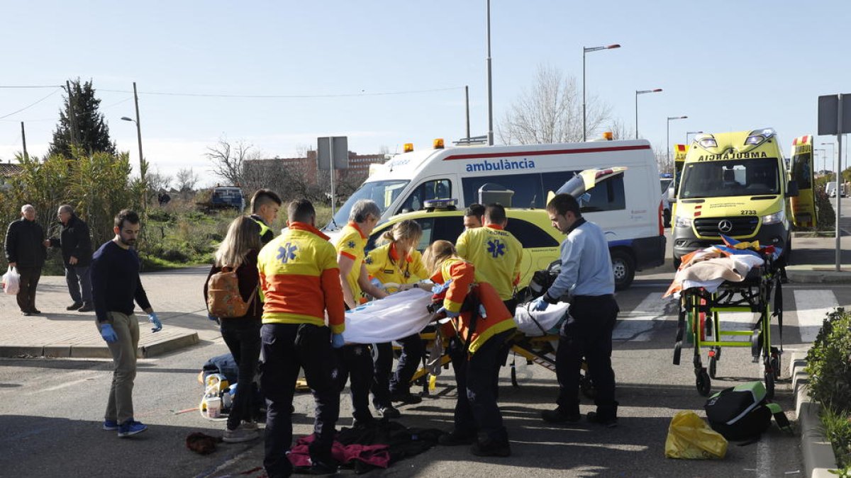 Vista del vehicle, amb l’impacte al parabrisa, i al fons, l’atenció dels serveis d’emergències a la vianant ferida.
