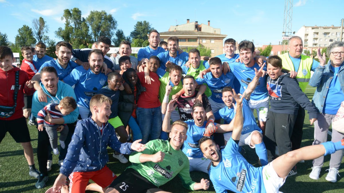 Els jugadors de l’Alcarràs celebren el campionat a la gespa després del partit.