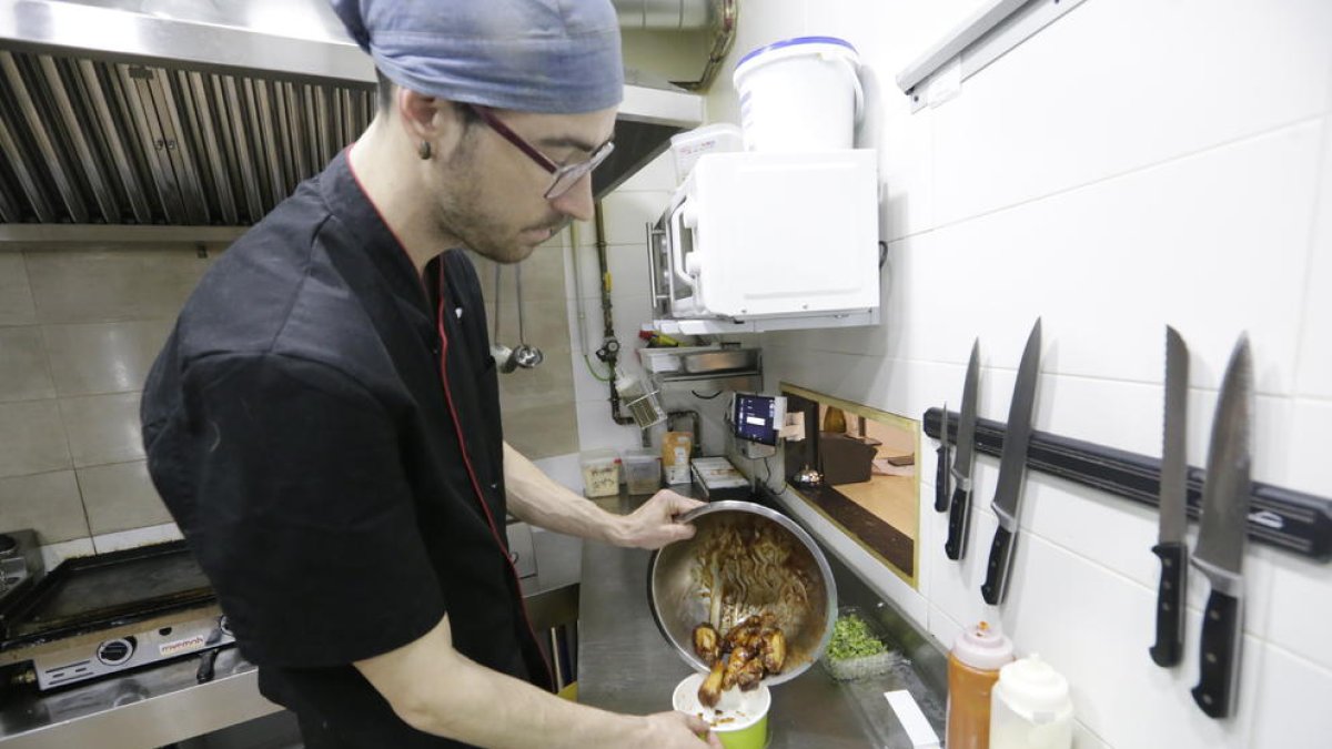 Un cocinero del restaurante ‘Des-Tapa’t’ de Lleida guardando la comida en un táper.