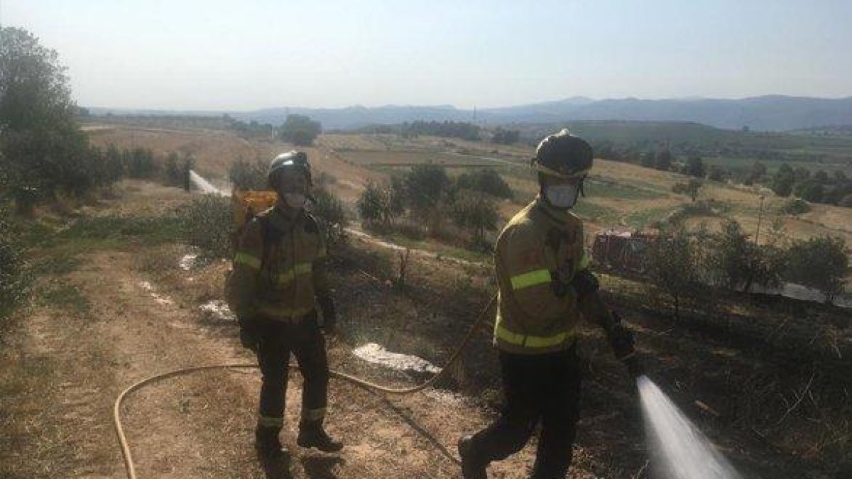 Dos bombers remullen la zona cremada.