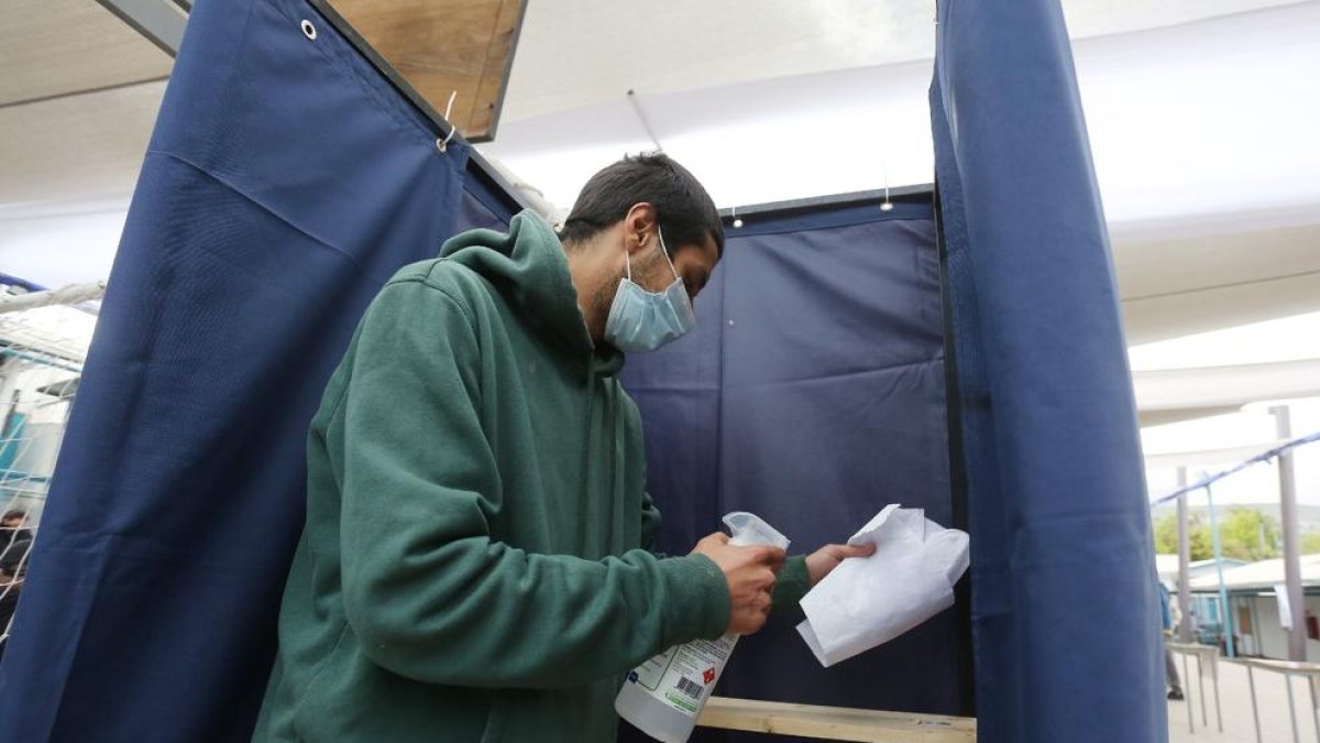 Un hombre desinfecta una cabina de votación en un colegio electoral en Santiago de Chile.