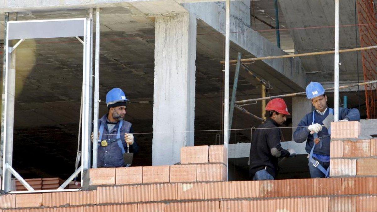 Tres trabajadores de la construcción, en la obra de un edificio de viviendas.