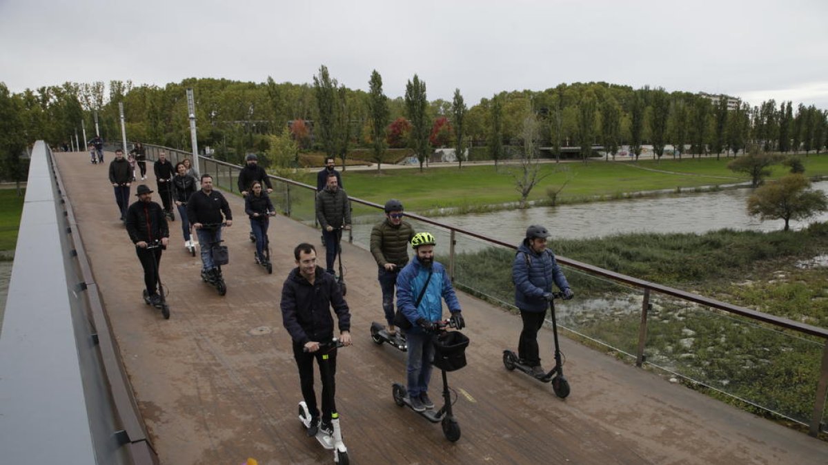 Usuarios de patinetes eléctricos circulando por una pasarela.