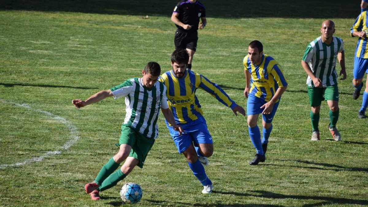 Un jugador del Alguaire controla el esférico pese a la presión rival.