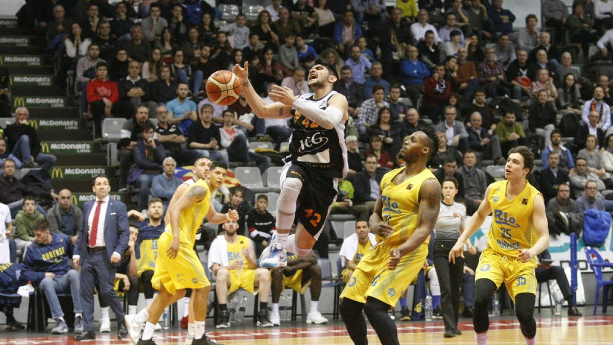 Sergi Quintela entra a cistella en una acció del partit d’ahir, davant l’oposició del jugador de l’Ourense Javon Masters.