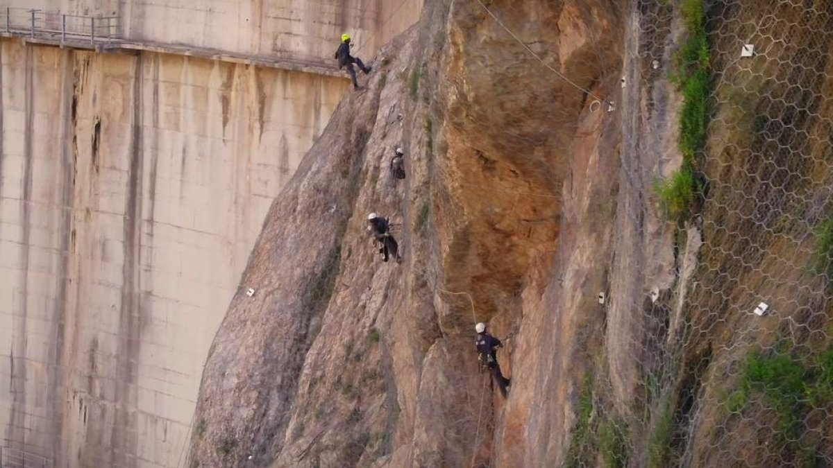 Las obras para colocar redes y garantizar la sujeción de la ladera al lado de la presa del pantano de Canelles y, a la derecha, el desagüe de fondo que se tiene que reparar.
