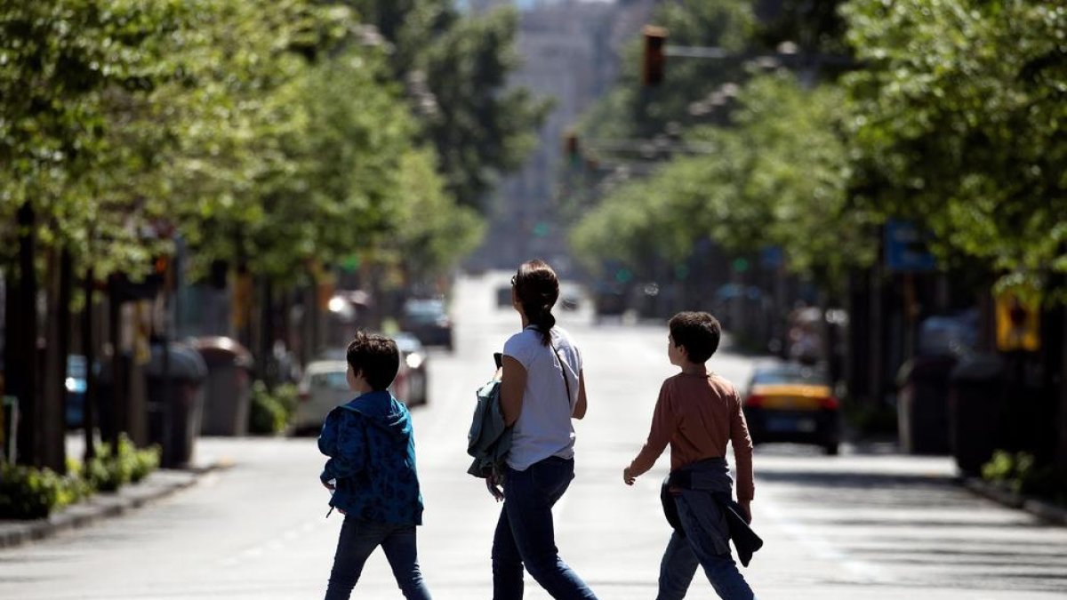 Tres personas cruzan una de las principales arterias de Barcelona, sin prácticamente tráfico, ayer.