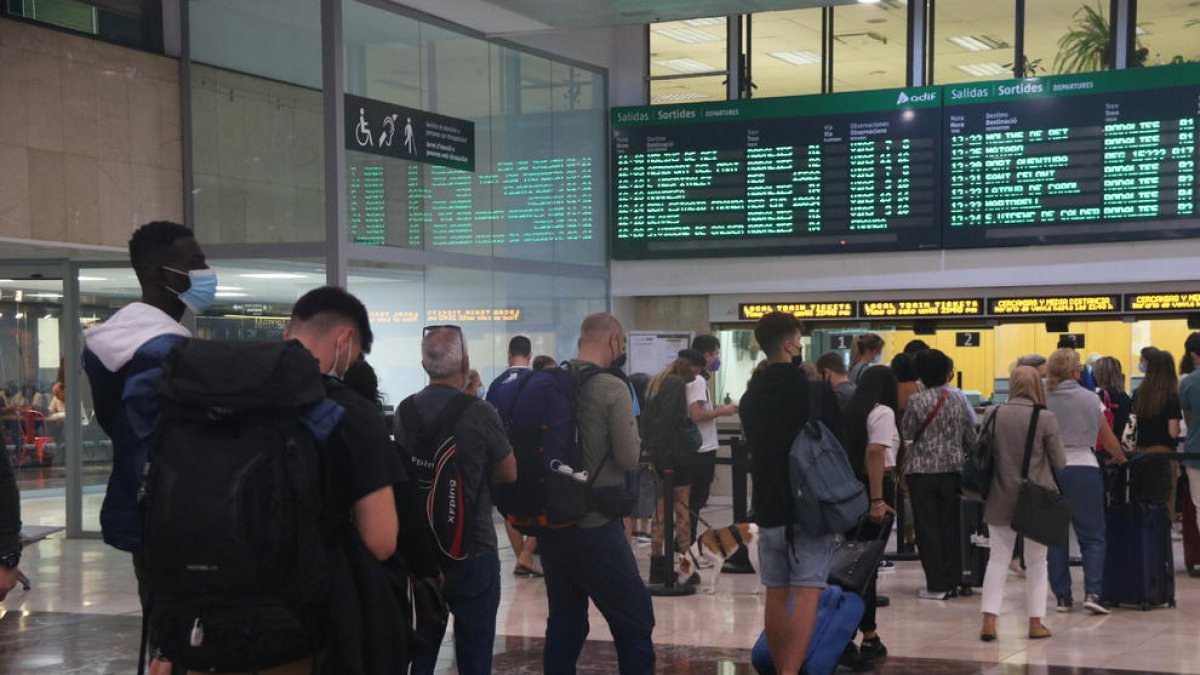 Diversos passatgers de Rodalies fent cua davant els mostradors d'informació a l'estació de Sants de Barcelona.
