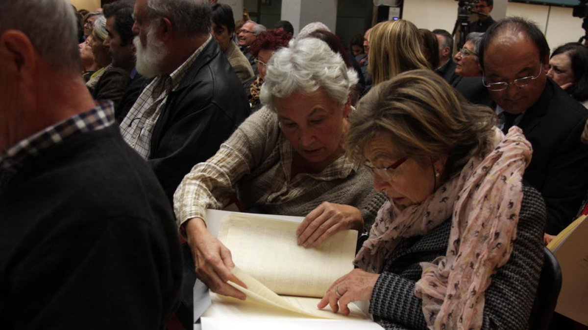 Dues dones revisen els 'papers de Salamanca' recuperats, en l'acte de lliurament del 3 de desembre de 2015.