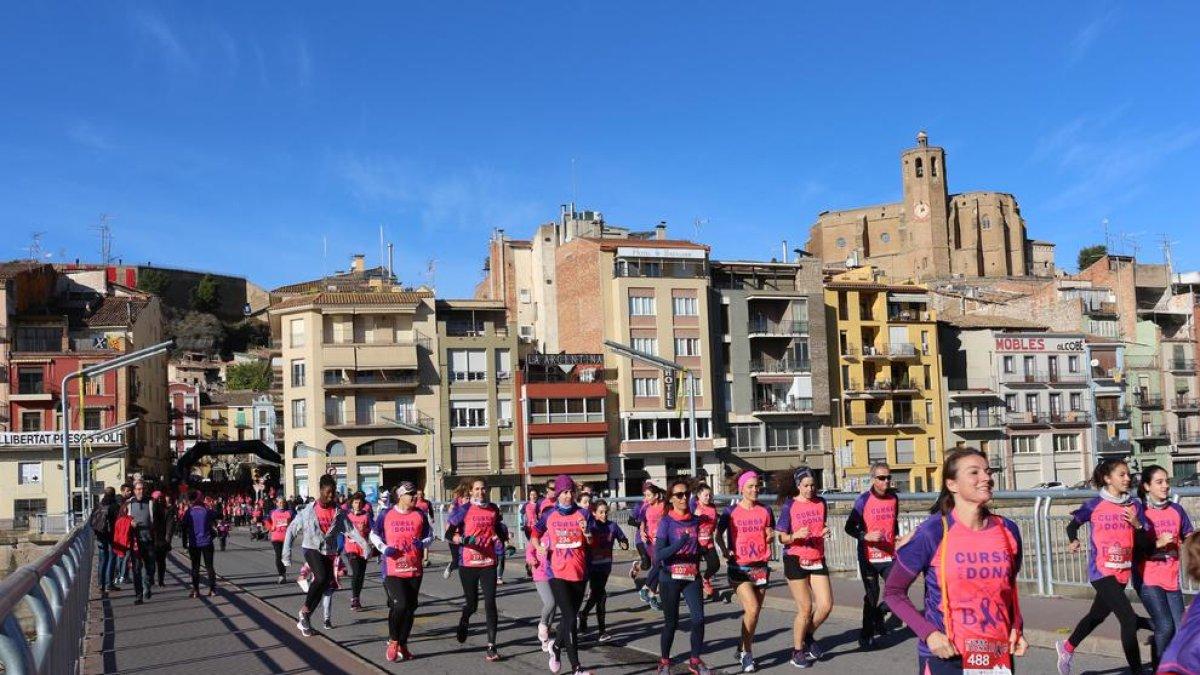 Un grup de participants de la Cursa de la Dona travessa el riu Segre al seu pas per Balaguer.