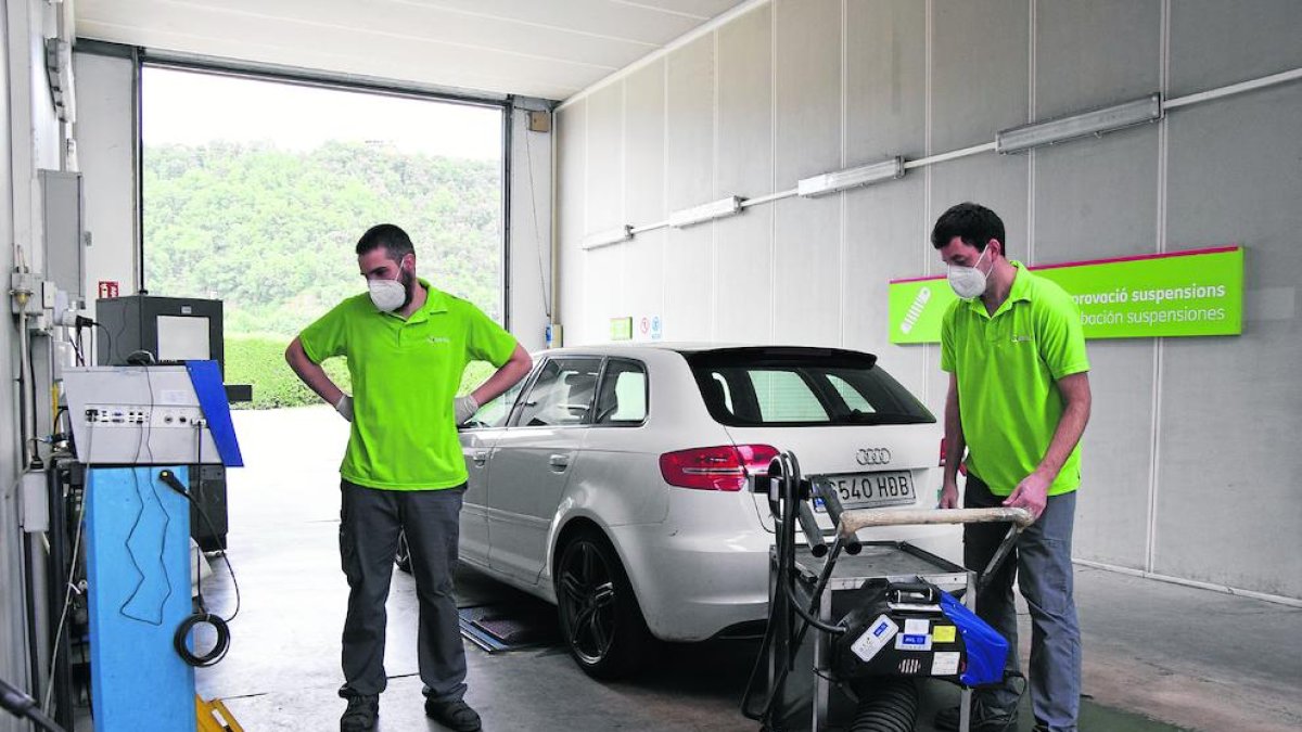 Dos operaris de l’empresa Certio revisen un vehicle a l’estació d’ITV de Montferrer.