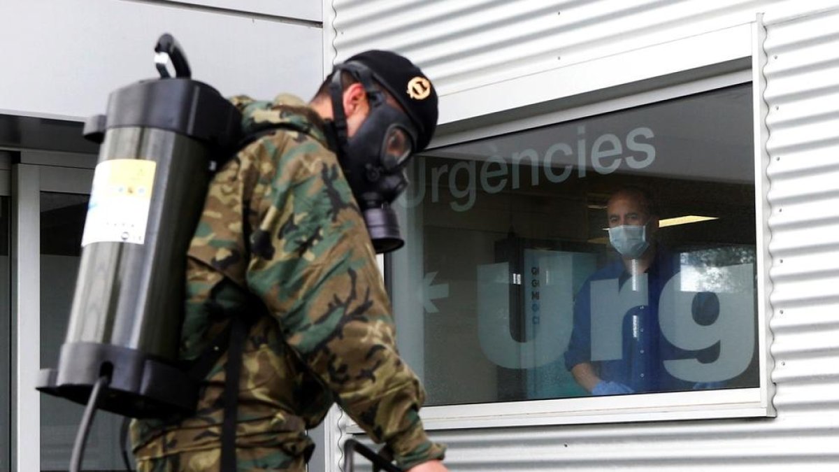 Un paciente observa la actuación de miembros del Ejercito de Tierra que trabajan desinfectando los alrededores del Hospital Trias i Pujol (Can Ruti ) de Badalona