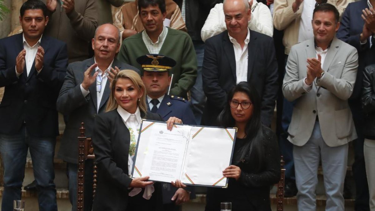 Áñez (izqda.) con el documento que convoca nuevas elecciones.