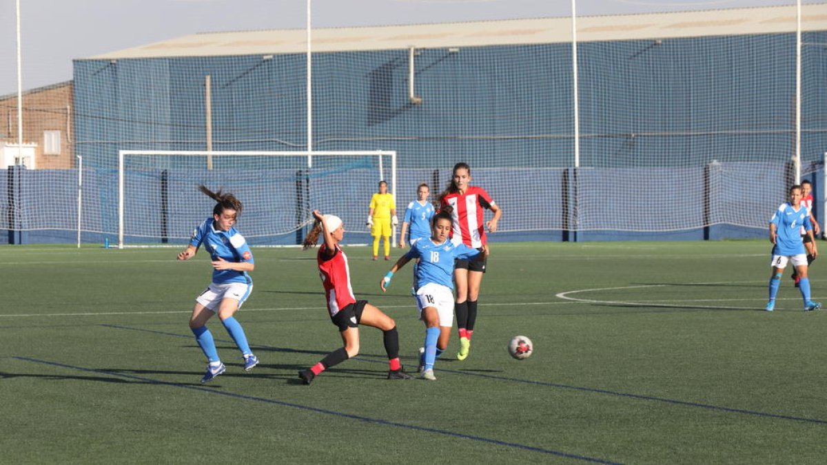Inés intenta controlar una pilota per a l’AEM davant de dos rivals de l’Athletic B.