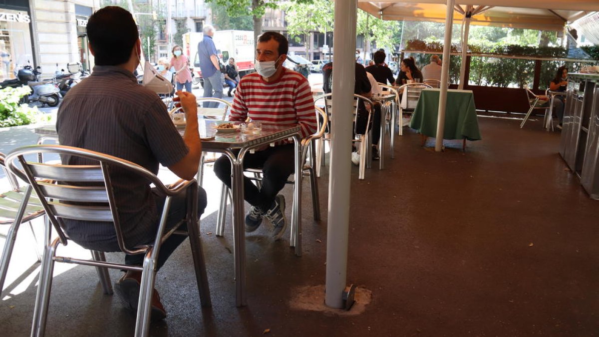 Dos personas toman algo en una terraza en la Rambla de Catalunya en Barcelona.