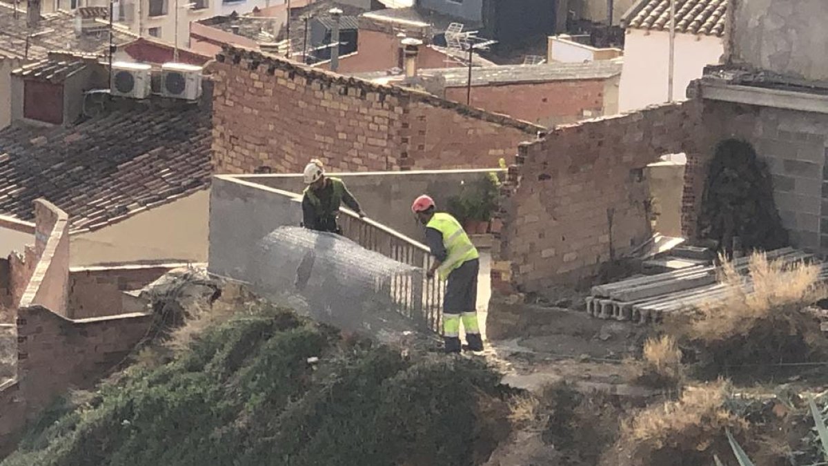 Operarios instalando mallas en el talud de la calle Obradores.