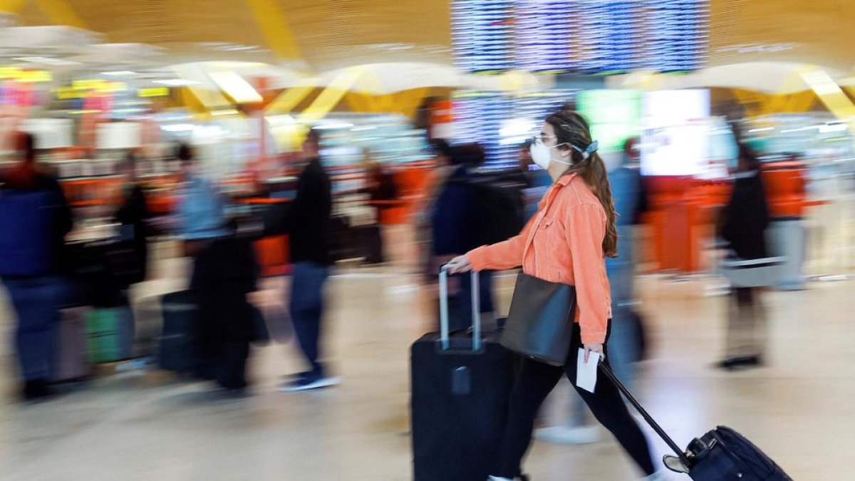 Una viajero con mascarilla en un aeropuerto.