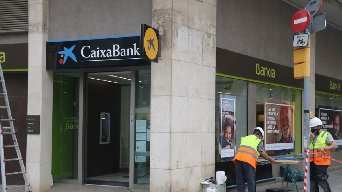 Operarios cambiando el logo de Bankia por el de Caixabank.