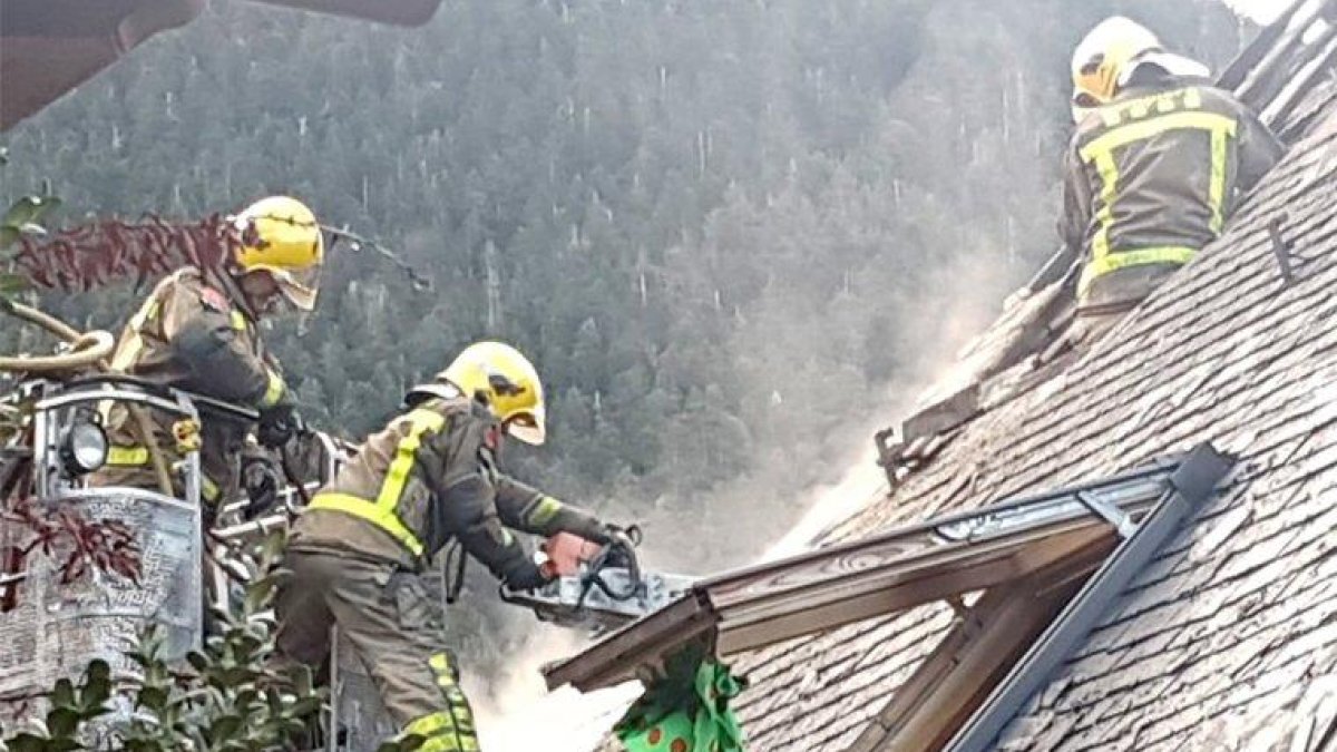 Bomberos sofocando las llamas originadas en una casa adosada.